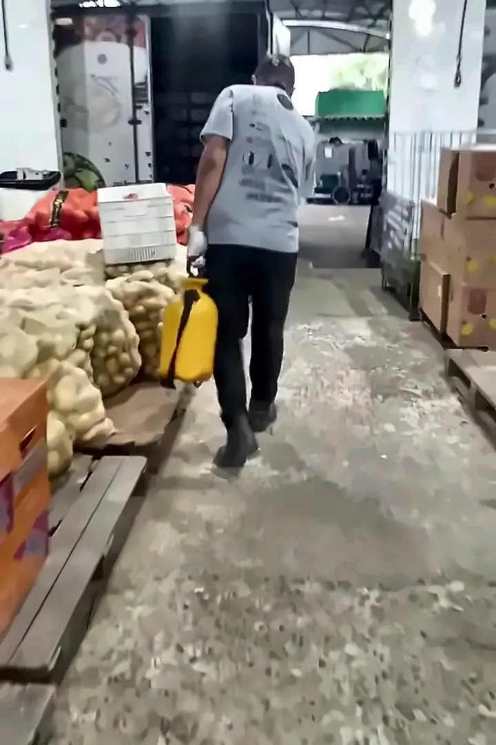 Técnico com pulverizador no corredor do galpão de hortifruti