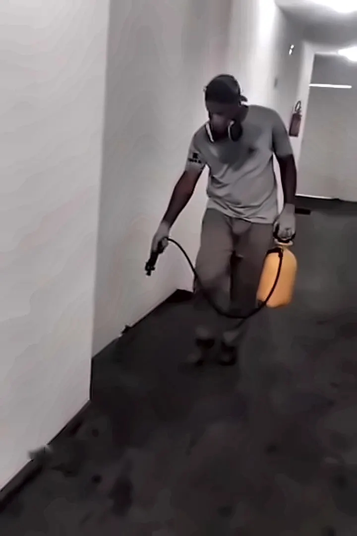 Técnico com pulverizador no corredor de um prédio